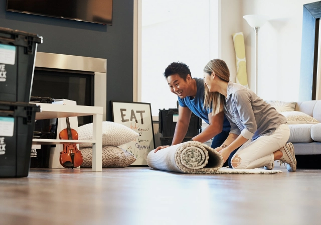 Man and woman couple extending carpet at home
